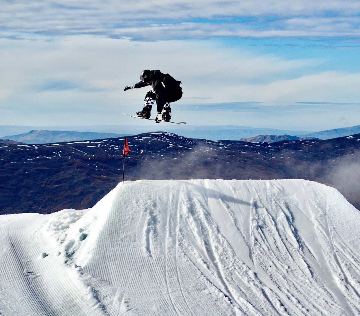 Daniel Yang grabbing his snowboard over a park jump